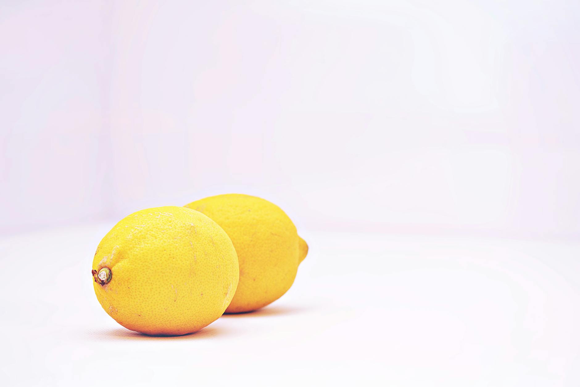 Dos limones vibrantes sobre fondo blanco minimalista, representando frescura y los vibradores de limón