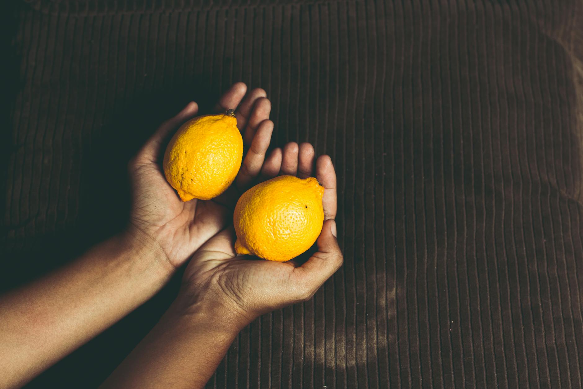 Una mano sosteniendo un vibrador naranja moderno contra un fondo minimalista púrpura