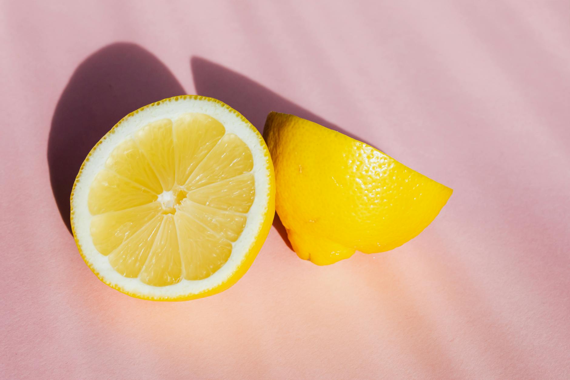 Mitades frescas de limón amarillo sobre fondo rosa con luz natural