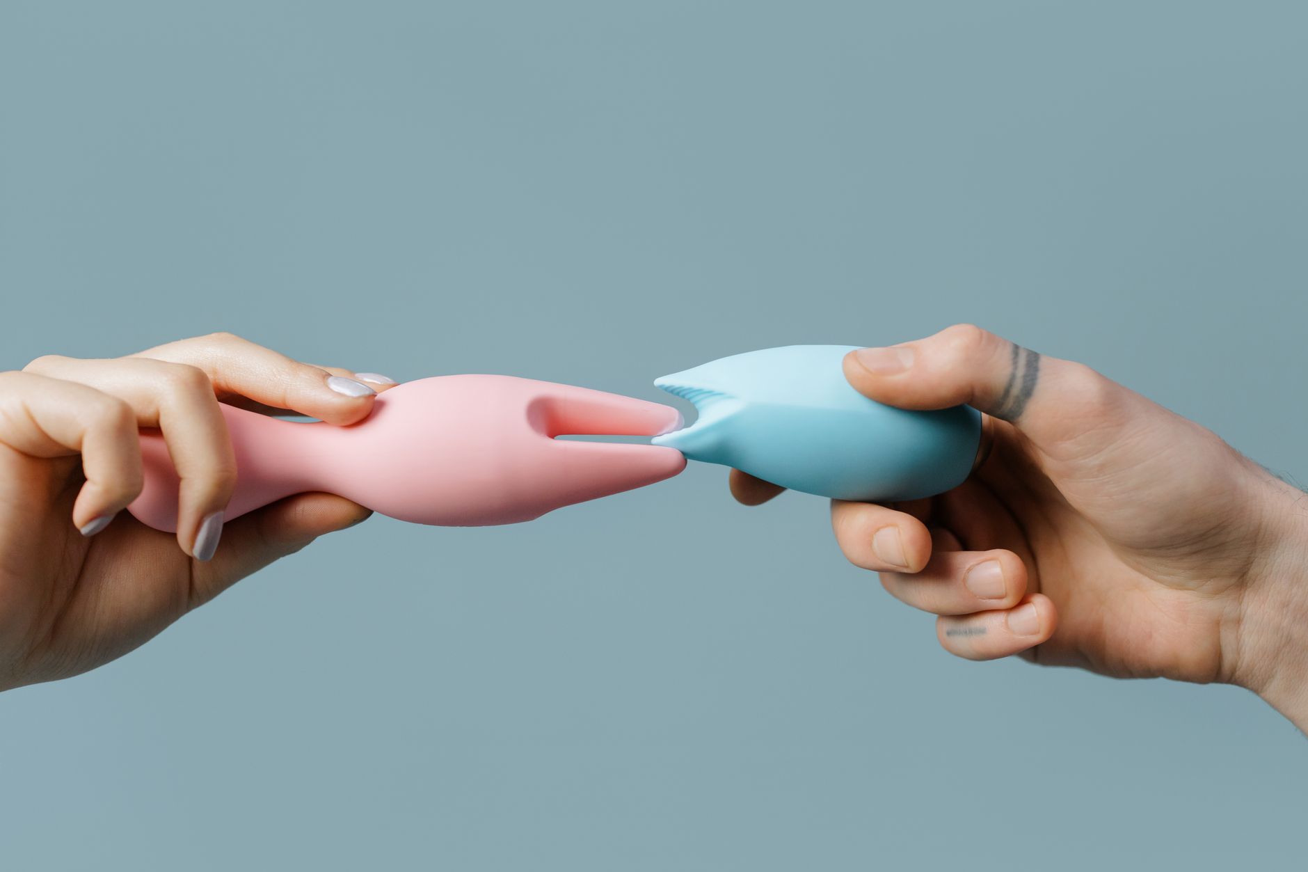 Mano sosteniendo un vibrador personal masajeador contra un suéter tejido en primer plano
