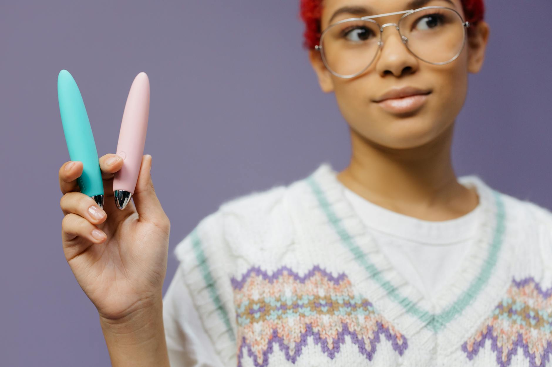 Vibrador de silicona azul sostenido en la mano contra un fondo púrpura