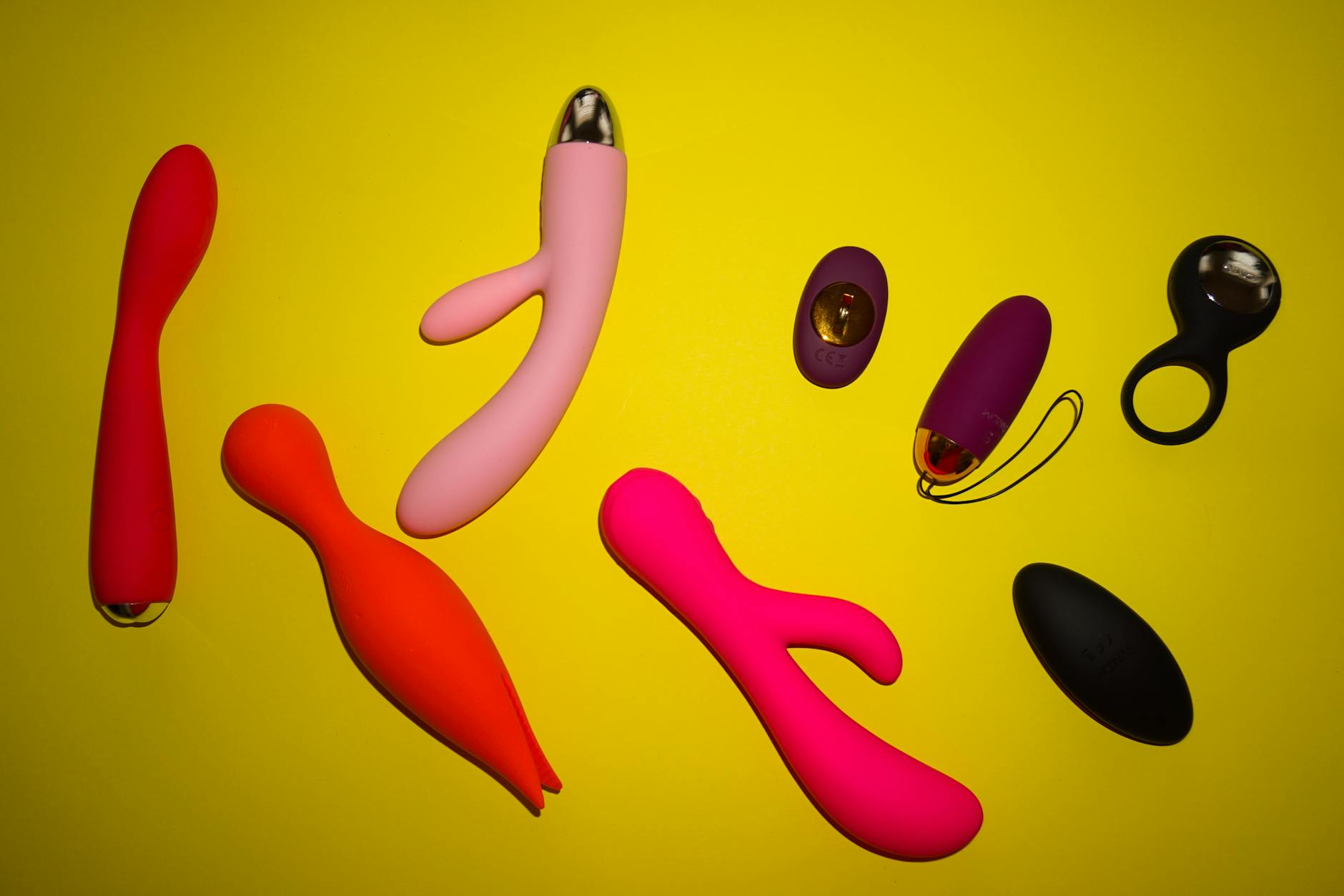 Vibrador de limón y otros juguetes de silicona en diferentes colores sobre fondo amarillo brillante